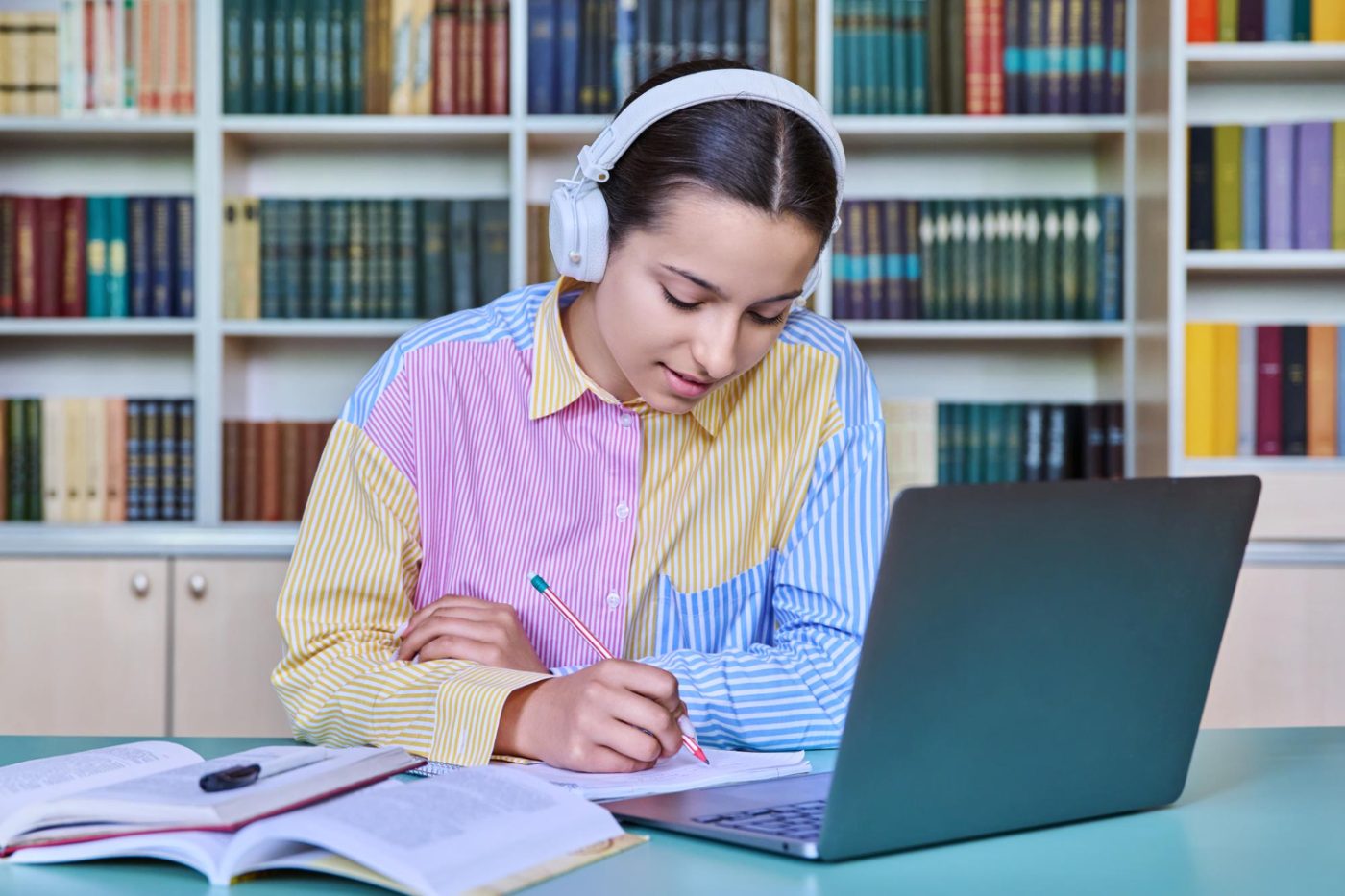 Student studying with headphones and laptop in a library