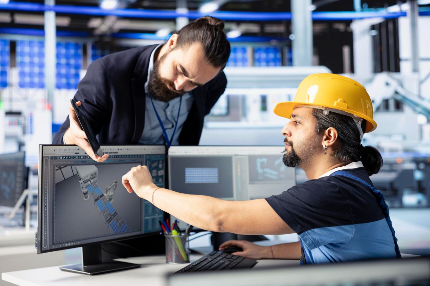 Engineer and operator reviewing CAD machinery models at a workstation