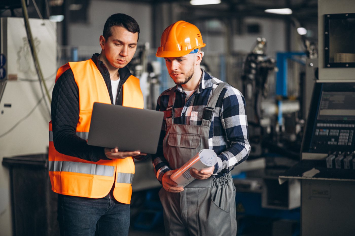 Supervisor and technician reviewing procedures on a laptop on the factory floor